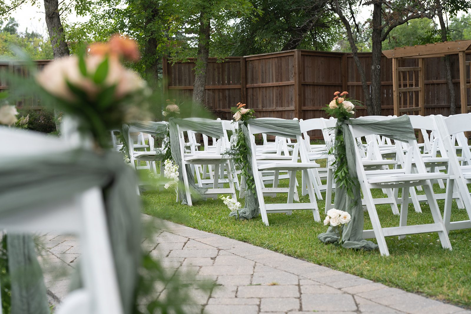 White ceremony chairs lining the stone aisle for an outdoor wedding at Breezy Bend Country Club