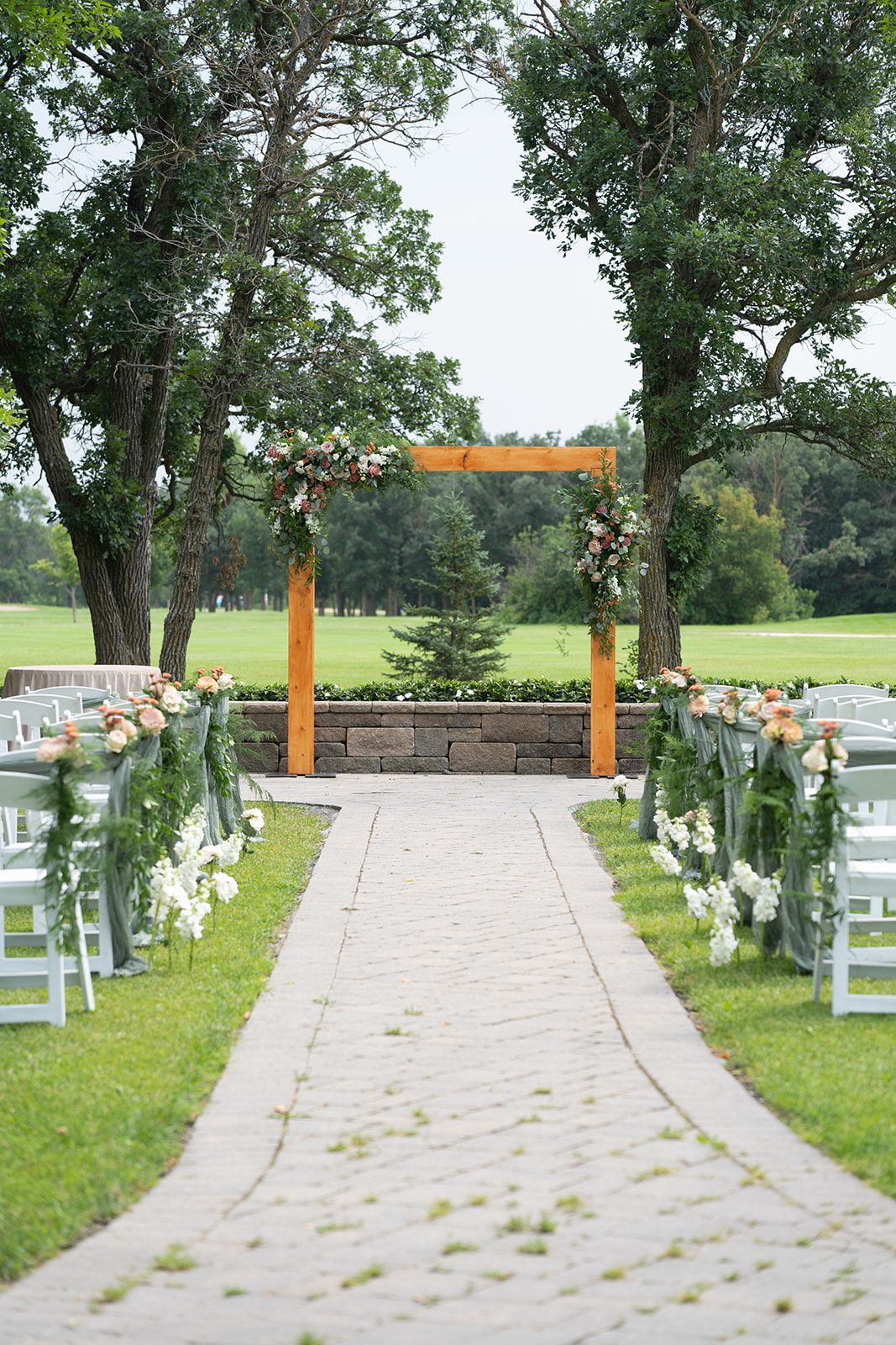 Outdoor ceremony site at Breezy Bend Country Club with a wooden arch framed by mature trees